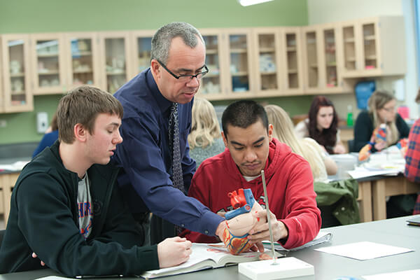 Professor working with students in a classroom setting