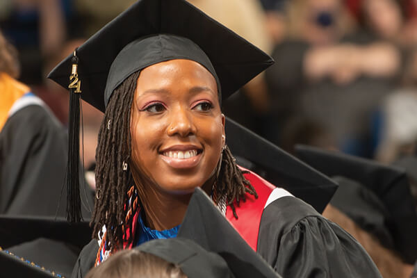 Student dressed in a cap and gown in a crowd of students at commencement