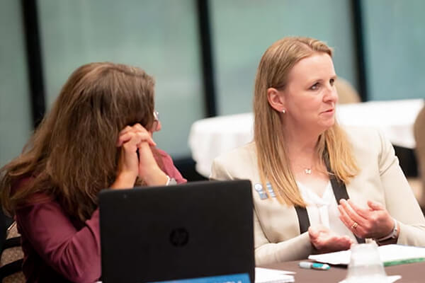 Two people speaking at table during a board meeting.