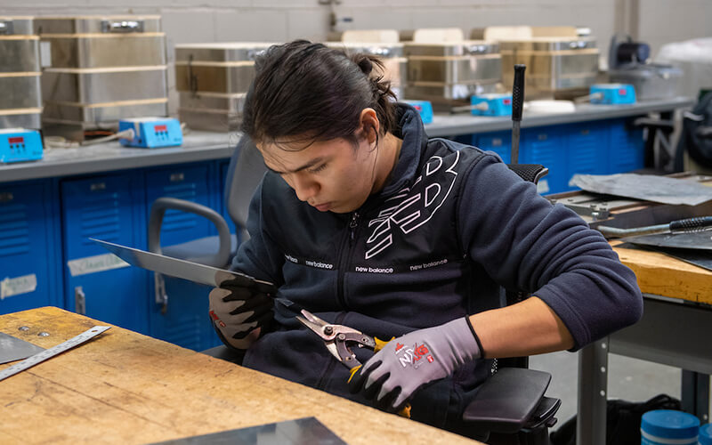 A student adjusting a piece of metal with a pair of handheld metal cutters