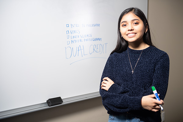 High school student posing in front of a board