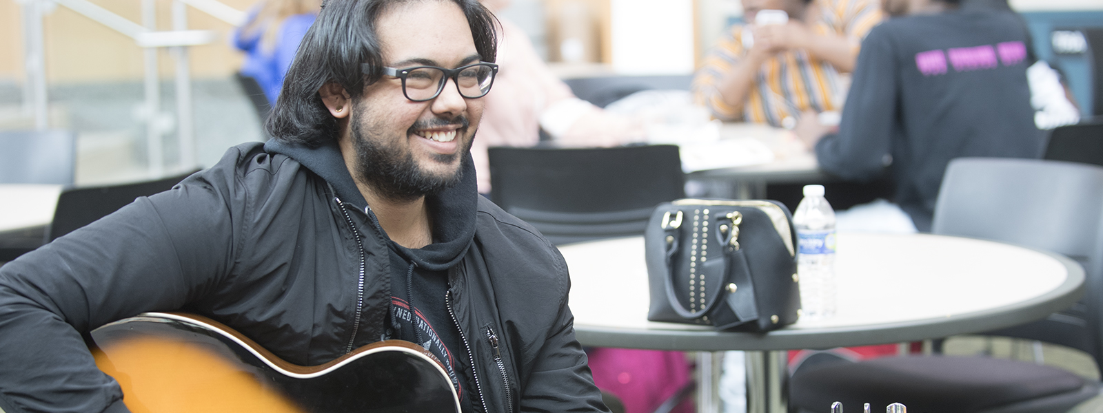 Student with guitar sitting in the Jobe lounge