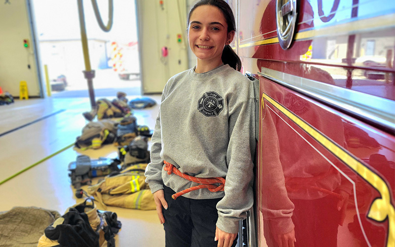 A student stands next to a firetruck