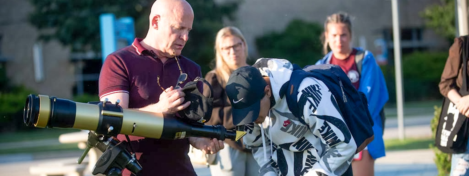 Students outside looking through a telescope.