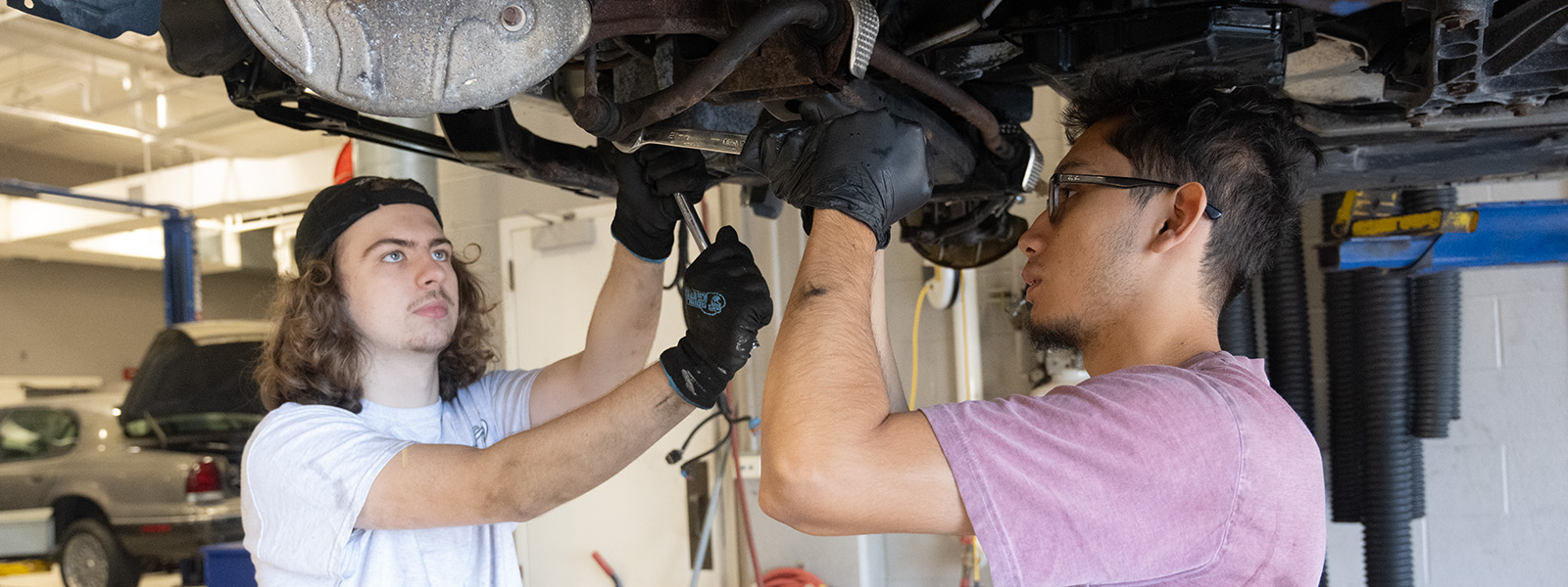 two students working under a car