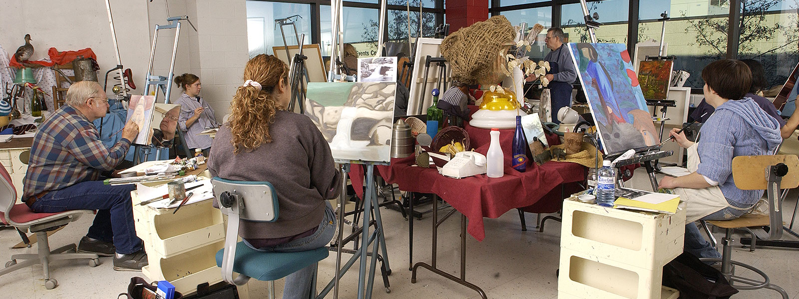 Art studio where people of various ages painting on canvas.