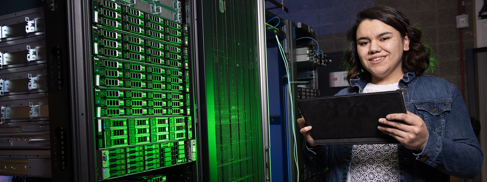Student holding a tablet near a server rack