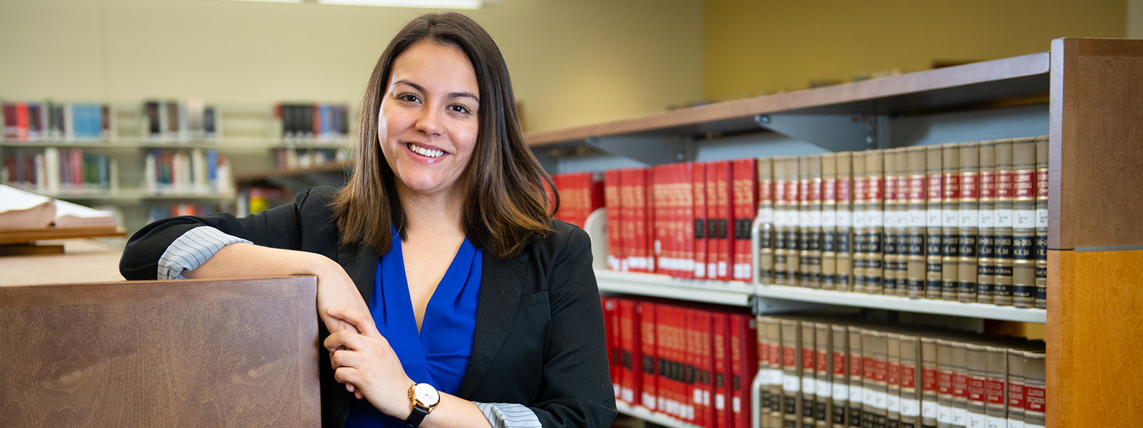 Paralegal student standing by bookshelves containing law books