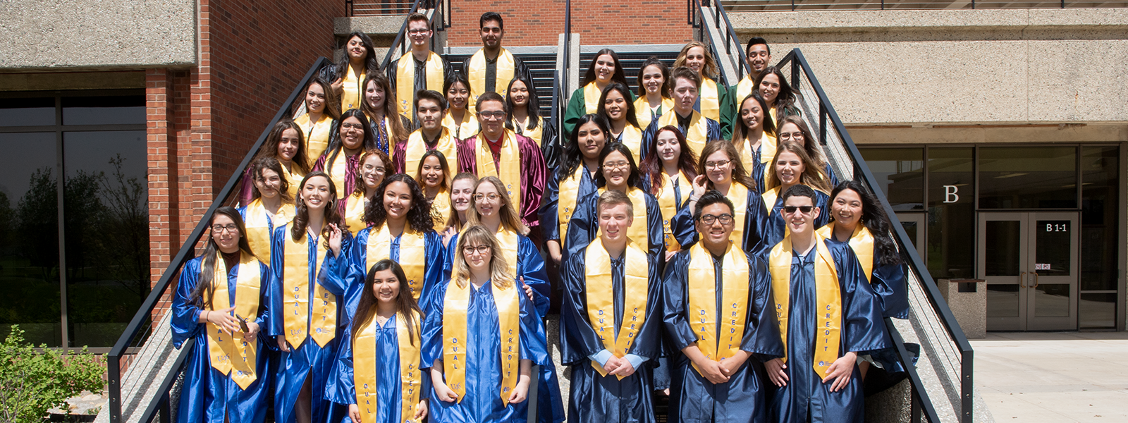 Group of over 30 dual credit students wearing graduation robes and stoles