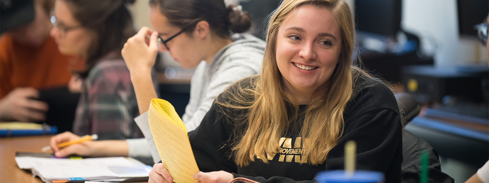 student in class with paper in hand