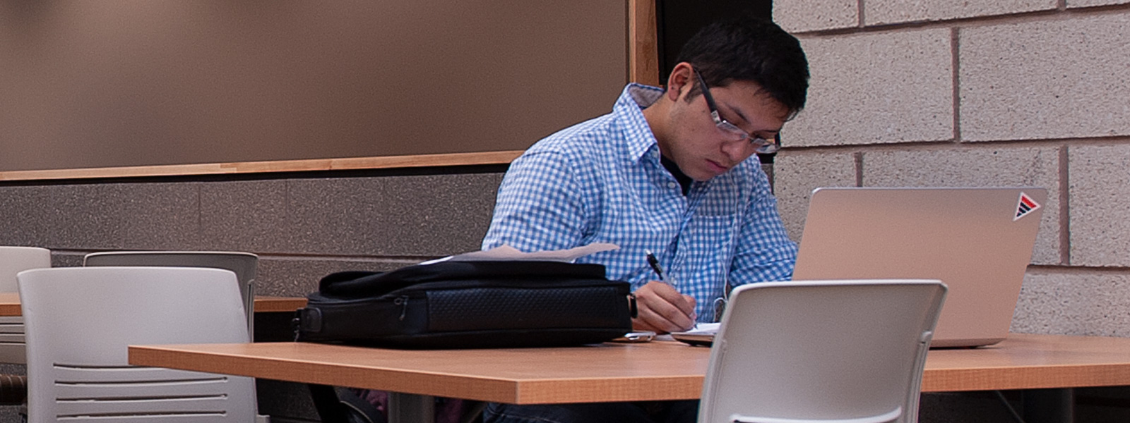 Student at desk working on computer doing work.