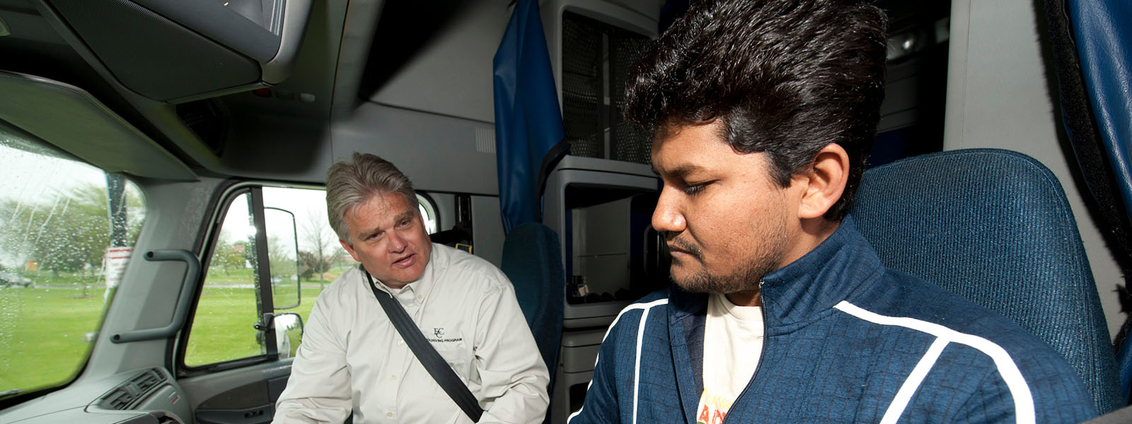 A truck driving instructor is teaching a student how to properly operate a truck.