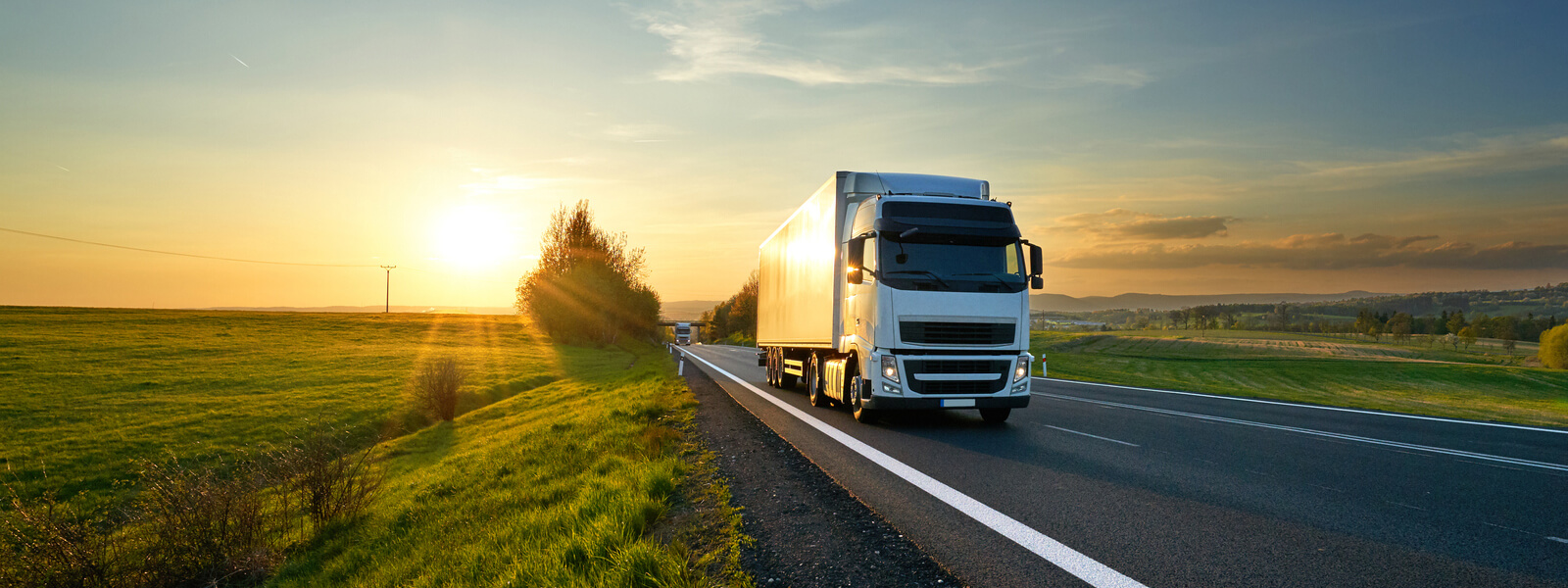 Trucks driving down the highway at sunset